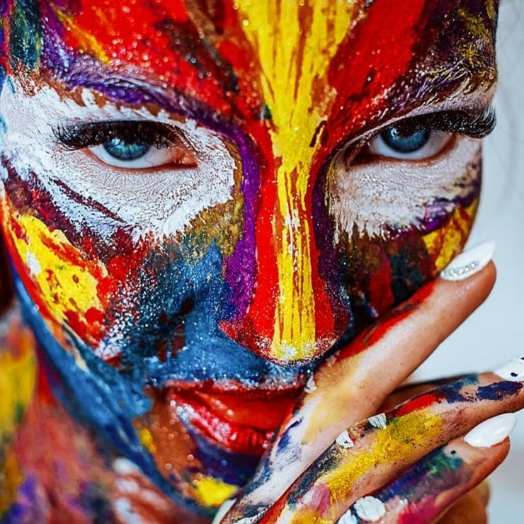 Woman covered in colorful pain like a bird