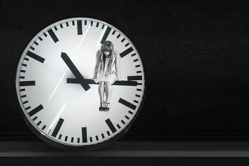 Woman sitting on large clock hand