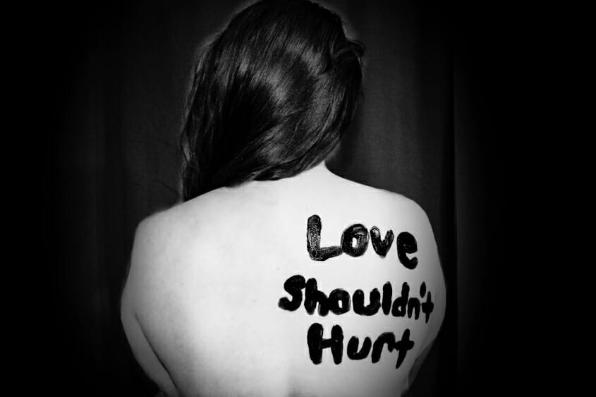 Love Shouldn't Hurt written on woman's bare back