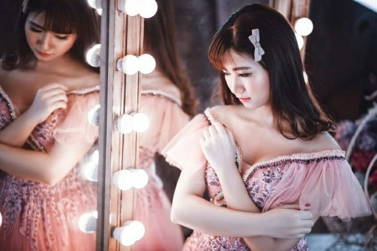 Shy Asian ballerina by the mirror
