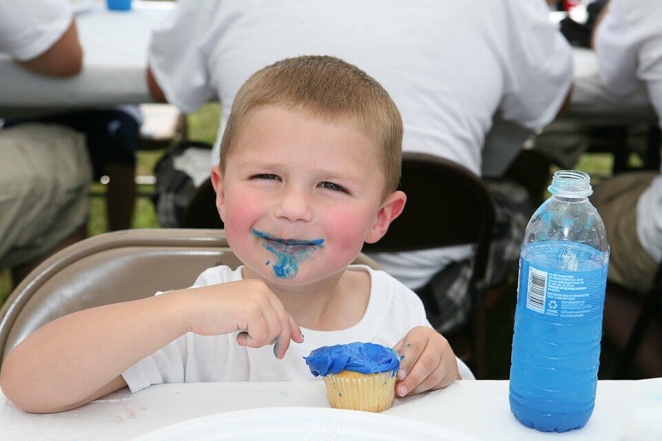 Overweight child eating cupcake with blue icing