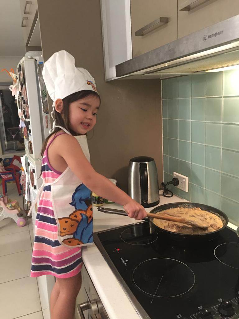 Little girl cooking in an apron and chef's hat