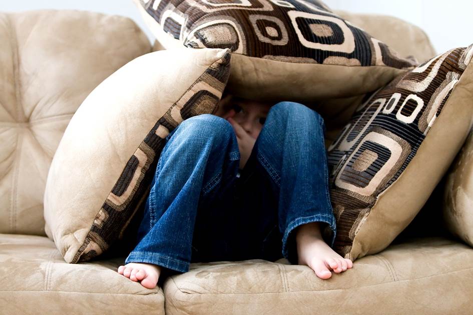 Boy hiding behind cushions