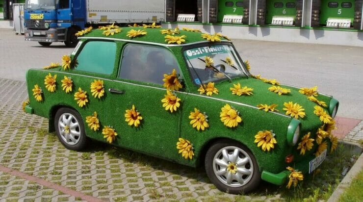Car covered in grass and sunflowers