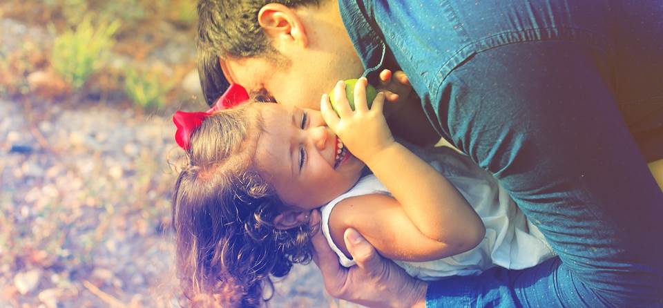 Father kissing giggling daughter