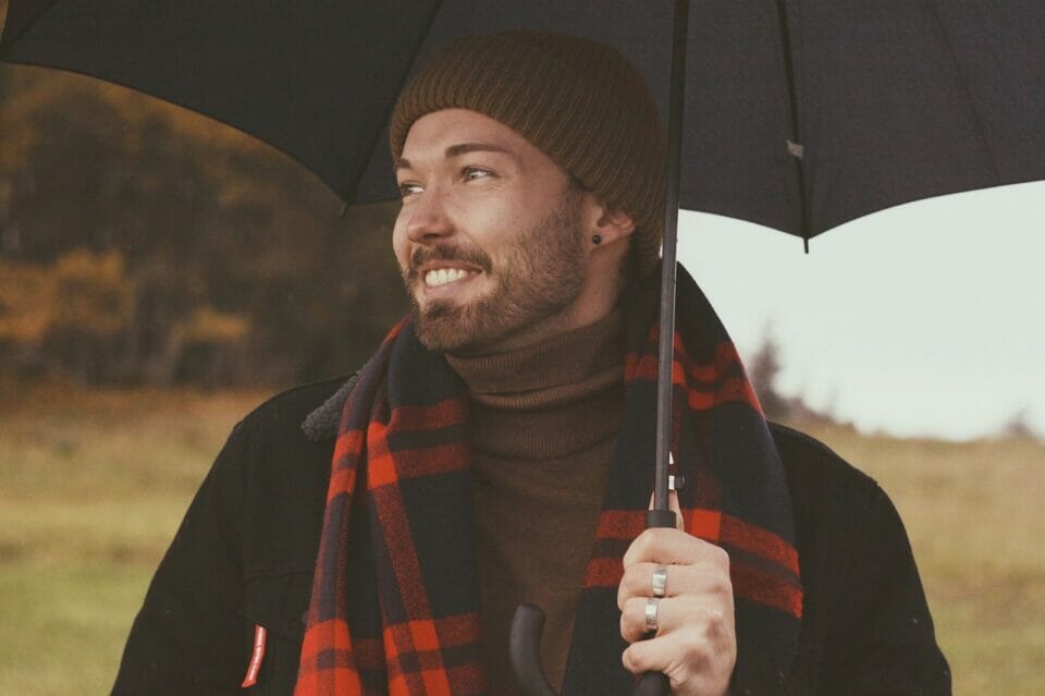 Man smiling happily under umbrella