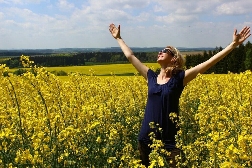 Woman raising her arms happily in a field of flowers