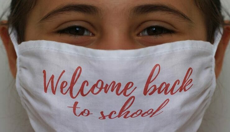 Girl with mask saying 'Welcome back to school'