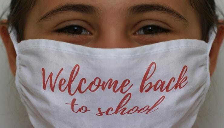 Girl with mask saying 'Welcome back to school'