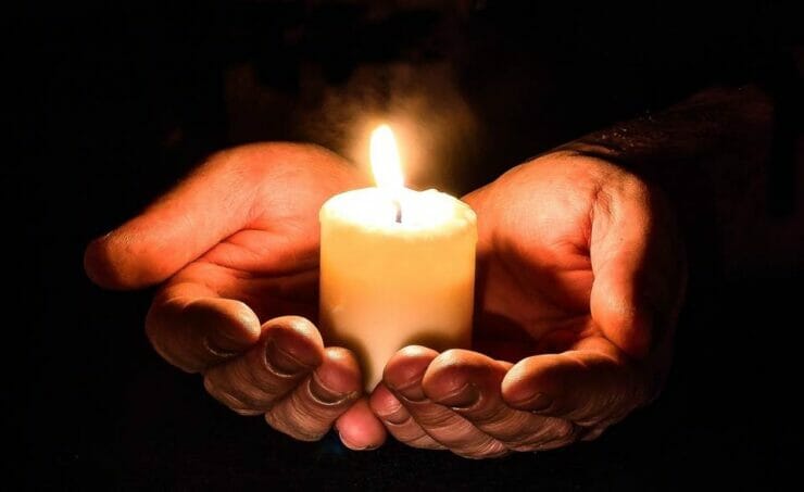 Hands holding a candle in the dark