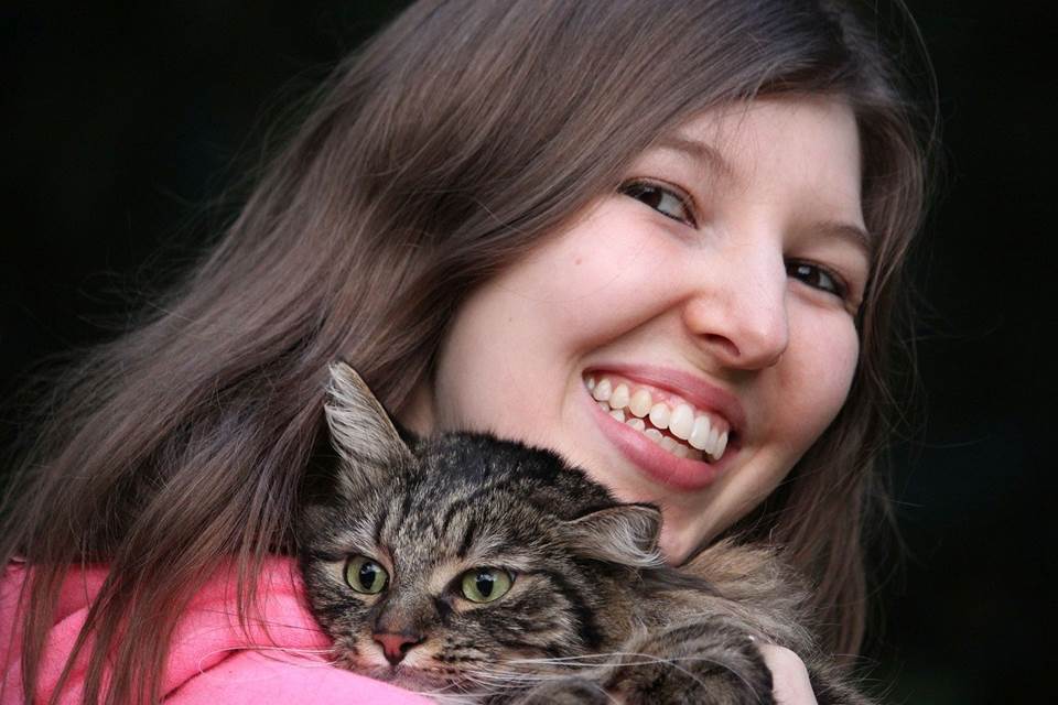 Woman holding a cat and smiling happily