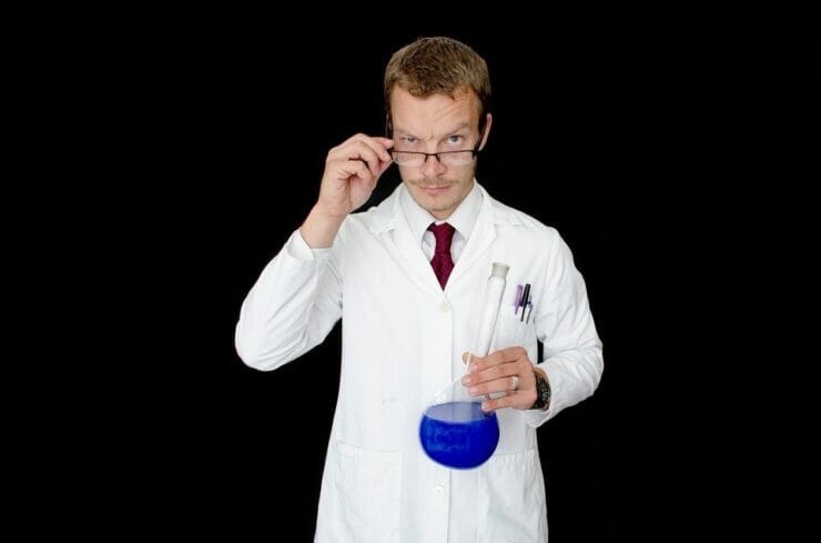 Man in lab coat holding a beaker with blue liquid