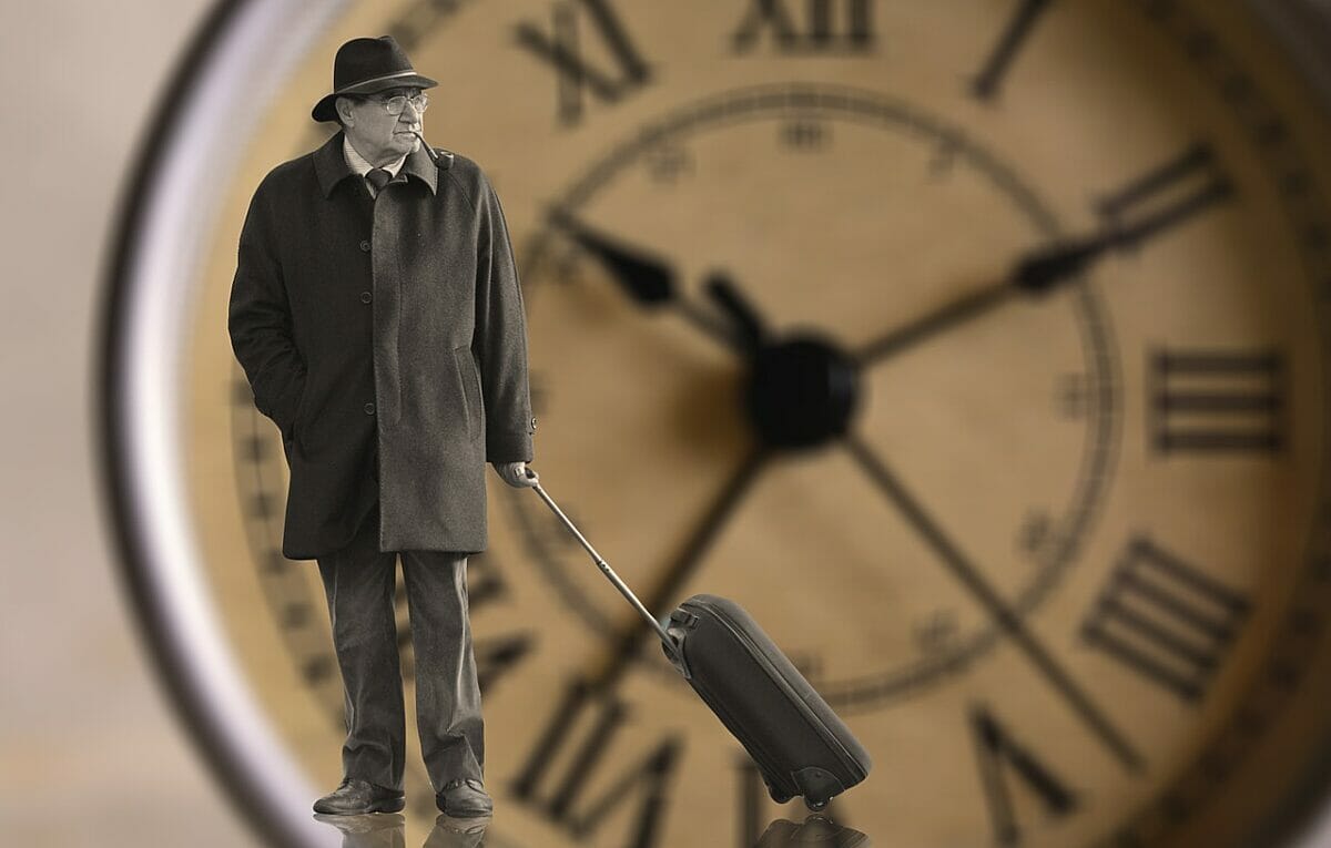 Old man with a suitcase in front of a big clock - a lifetime perspective