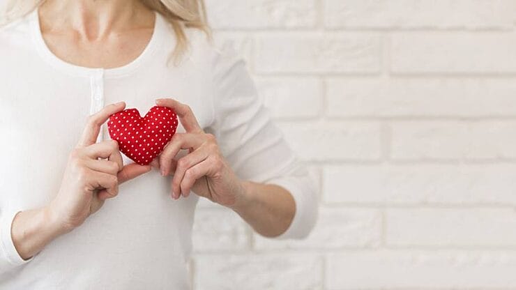 Woman holding a red heart decoration for kindness day
