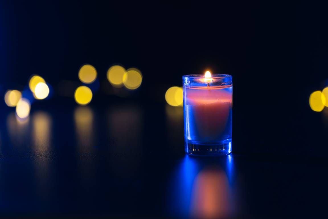 : A single candle glowing in darkness, representing inner light and resilience.
