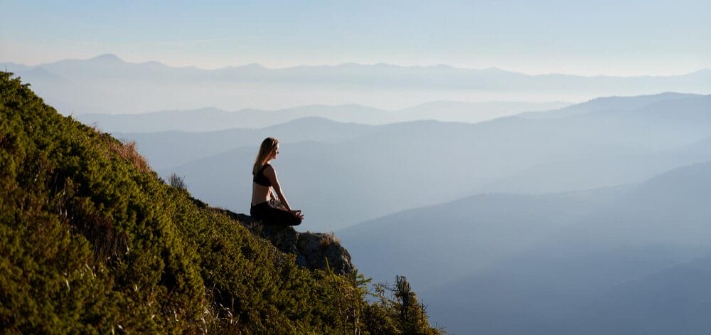 A women sitting in silence on a mountain reflecting on life