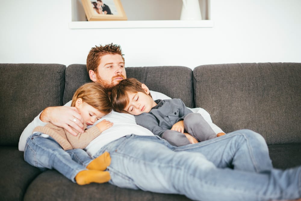 Little boys sleeping on their father on the couch